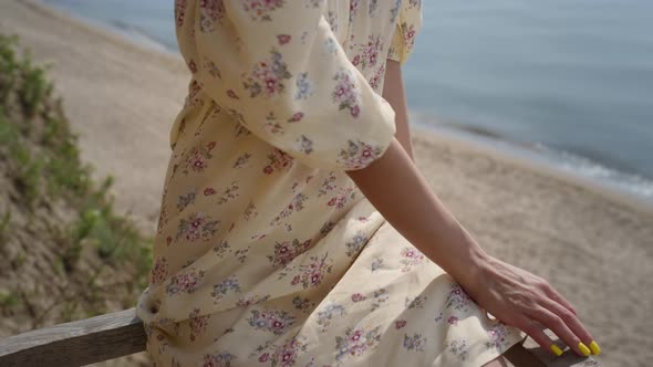 Adorable Woman Relax on Beach Wearing Flowery Dress Closeup alt