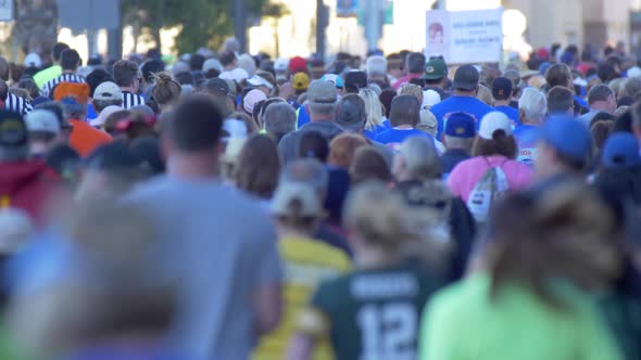 The back of a crowd of people running in a 10K race. alt