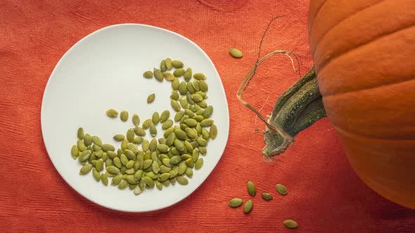 Organic raw pumpkin seeds are falling into white ceramic plate  alt