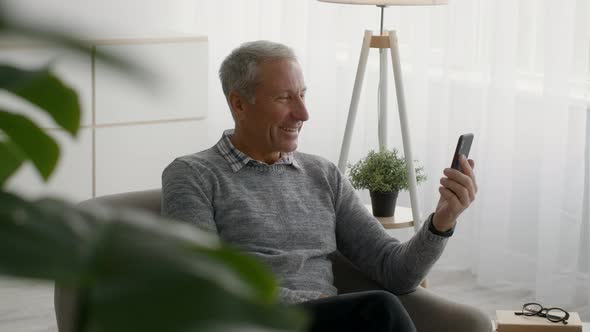 Happy Senior Man Making Video Call With Smartphone At Home