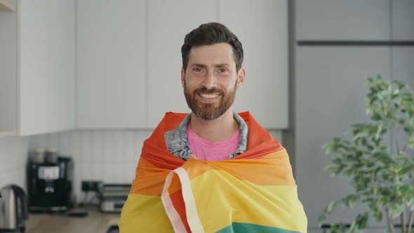 Portrait Shot of Middle Aged Smiled Gay Man Wearing Rainbow Flag Over His Shoulder and Looking at alt