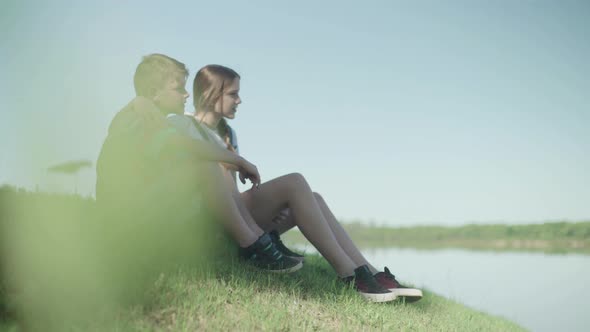 Children sitting together on hillside looking at view alt