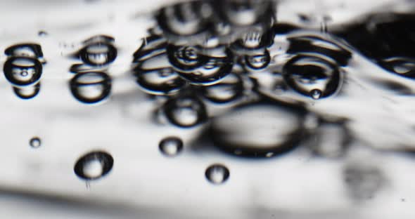 Liquid Poured into Water Creating Bubbles that Rise to the Surface alt
