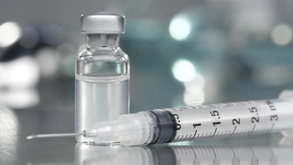 Vial filled with liquid vaccine in medical lab with syringe alt