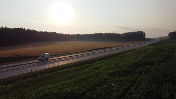 Aerial view of a beautiful country expressway with a small cargo van passing by at dawn. alt