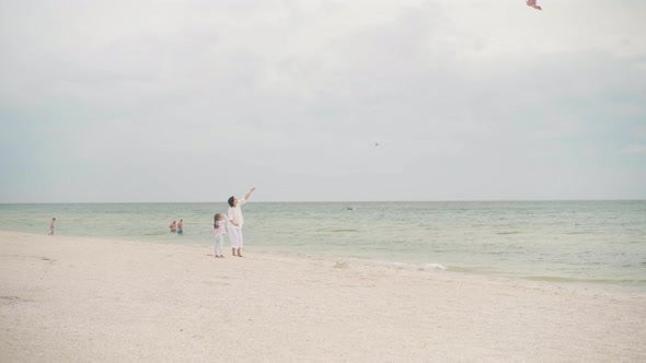 Mother with Little Daughter Playing Kite On Sea Beach Happy Caucasian Family With One Child Have Fun