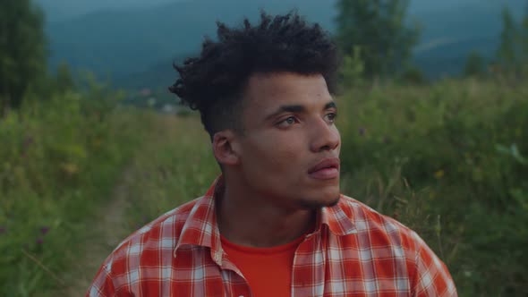 Portrait of Hipster Black Musician Playing Djembe Drum on Mountain Hill at Sunset alt