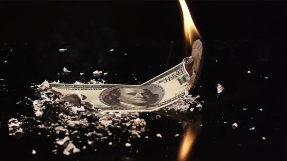 One hundred dollars is flaming and falling on a black table