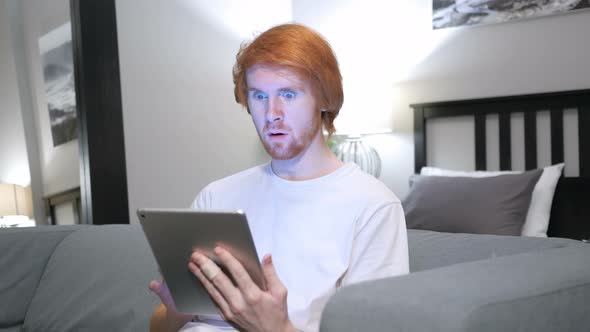 Shock, Wondering Redhead Man Using Tablet in Bedroom alt