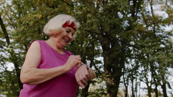 Senior Sport Runner Woman Using Smart Watch, Tapping Touchscreen, Tracking Distance, Checking Pulse alt