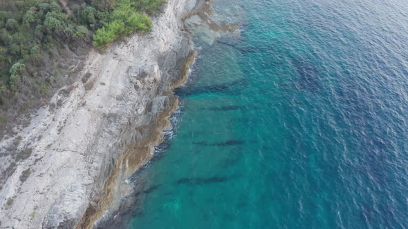 Aerial top down shot of a beautiful shore with turquoise clear water on the right side of the frame. alt