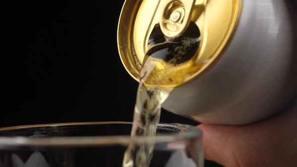 Pouring Cold Beer into a glass with water drops. Can of Beer close up. alt