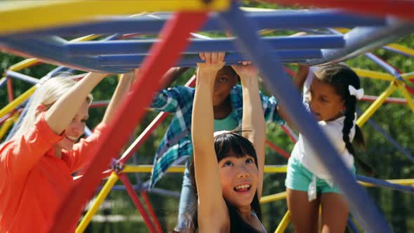 Trainer assisting schoolkids while playing in playground alt