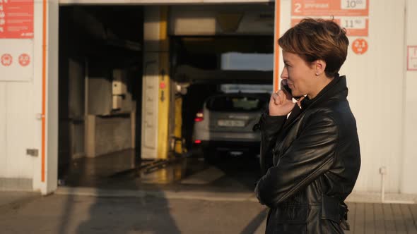Attractive Girl Talking on the Phone in the Background of a Car Wash