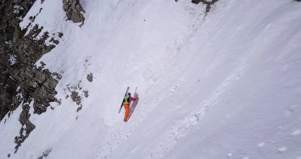 Aerial drone view of a mountain climber climbing up with crampons in the snow. alt