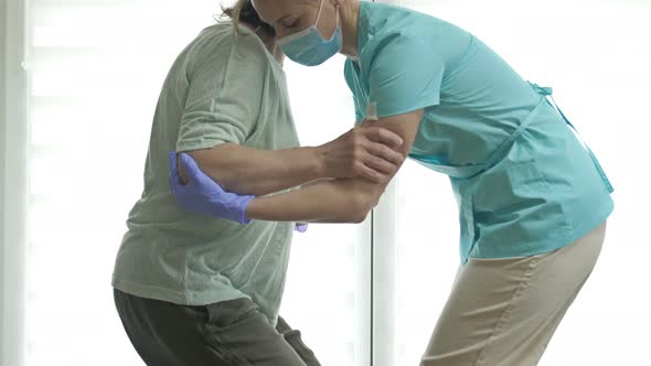 Doctor or Nurse is Helping an Elderly Woman to Get to Her Feet alt
