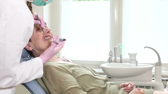 Smiling elderly woman giving high-five to dentist alt