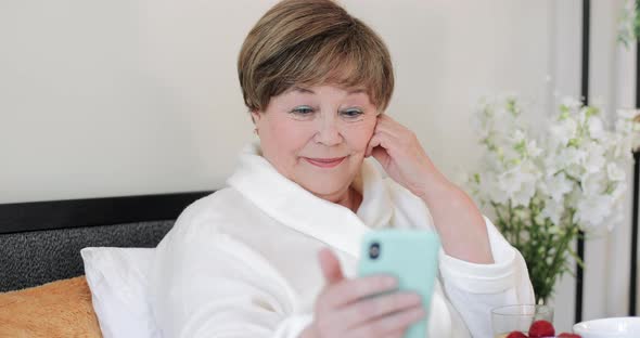 Close Up View of Old Woman Using Her Smartphone for Watching Photos. Good Looking Elderly Female in alt