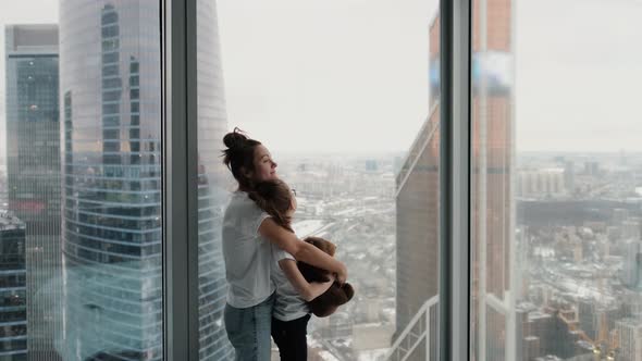 Mom and Daughter Spending Time Together in a Modern Apartment with Large Windows Overlooking the alt