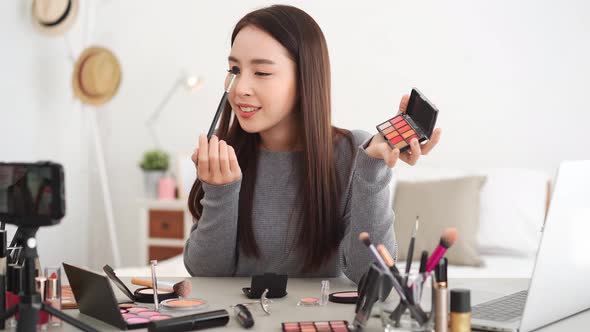 Young beautiful Asian woman professional beauty vlogger influencer doing cosmetic makeup tutorial