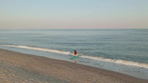 Beautiful Scene of a Woman Walking on Ocean Beach at Sunset