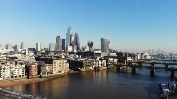 Flying over the Millennium Bridge towards the London's Financial District on a hazy sunny day alt