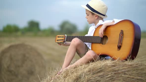 Little Boy on a Haystack with a Guitar