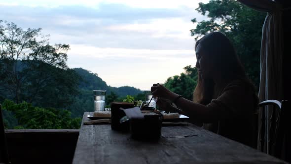 A woman having dinner and looking a beautiful nature view