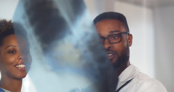 African Doctors Discussing Patient Diagnosis Looking at Xrays in Hospital alt