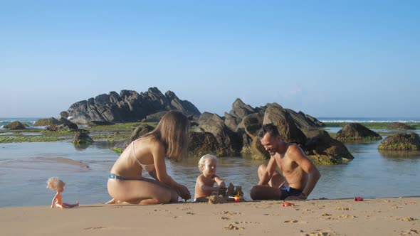 Husband Sculpts Sand with Wife and Child Swims in Ocean alt