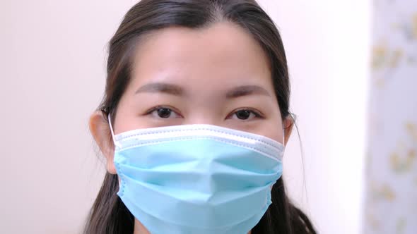 Beautiful Asian woman wearing a mask look camera and relaxing stay on the bed at home lifestyle and alt
