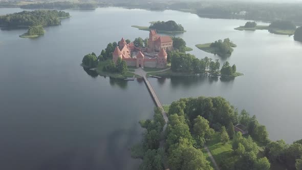 Aerial pan up view of medieval Trakai castle on island in lake Galve at sunrise summer Lithuania