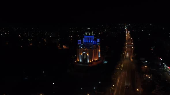 The Church Is Illuminated At Night By Colorful Lights On The Background Of The City. Night