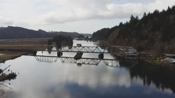 vintage arched railbridge over large Siuslaw river on Cushman town, Oregon. reversing drone view alt