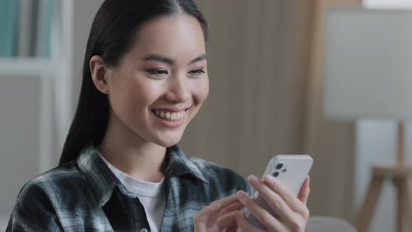 Home Portrait of Asian Woman Girl Blogger Looking at Mobile Phone Screen Smiling Swipe Checking Mail alt
