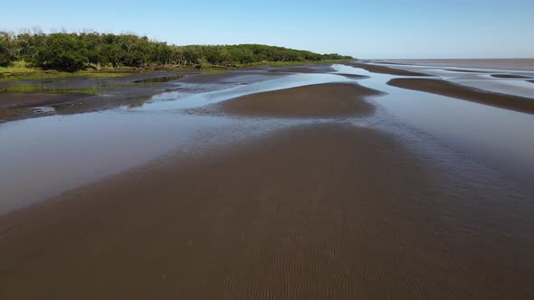 Rising forward aerial of sand banks and woodlands by Rio de la Plata alt