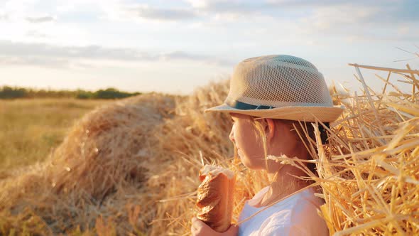 Hungry Child Eating Bread in Wheat Field, Summer Outdoor Lifestyle. alt