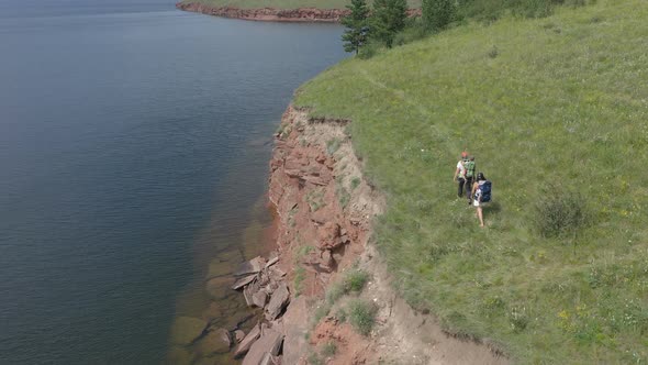 Aerial Shoot of Young Parents Walking with Young Children on a Mountain Cliff