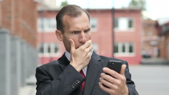 Businessman in Shock while Using Smartphone alt