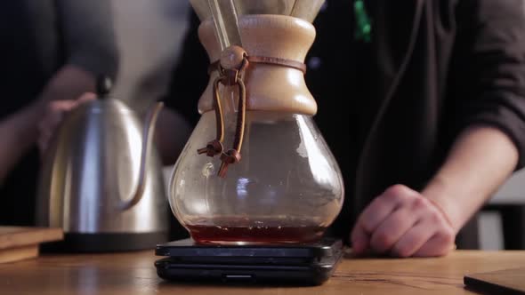 Barista pouring hot water into filter with coffee. Brewing coffee in a chemex