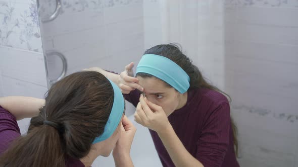 Girl Plucked Her Eyebrows in Front of the Mirror, in the Bathroom and Looks Satisfied alt