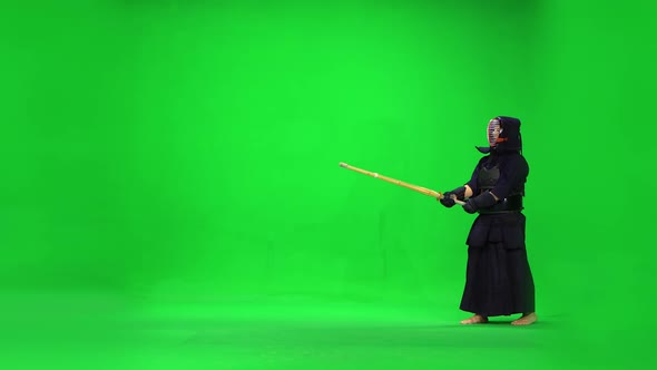 Masculine Kendo Warrior Practicing Martial Art with the Bamboo Bokken on Green Screen. alt