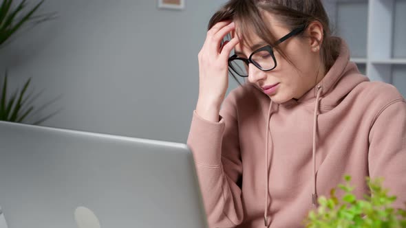 Fatigue and headache in a young woman working on a laptop. 4K. Tired woman.