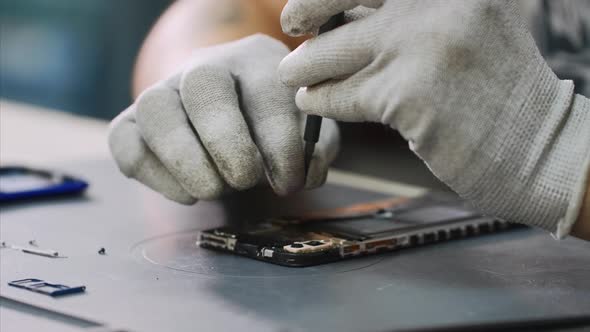 Repairman in White Gloves Disassembles Smartphone with Screwdriver in Workshop alt