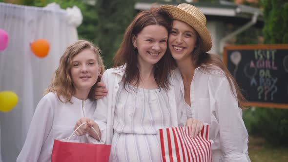 Portrait of Happy Pregnant Caucasian Woman Posing with Young and Teenage Daughter Outdoors alt