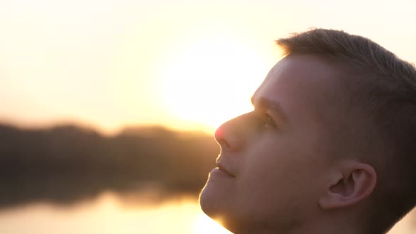 Close Up Portrait of Pensive Handsome Young Man Looking Up Enjoying Nature in Sun Rays at Sunset