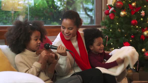Young mother and kids singing celebrating Christmas at home