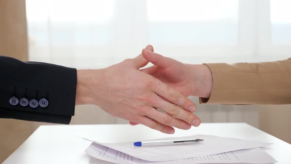 Realtor Gives Keys with House Shaped Breloque To Young Lady After Shaking Hands Above Table with alt