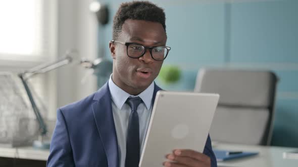 Portrait of Video Call on Tablet By African Man in Office alt