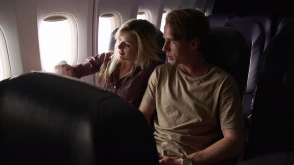Couple talking and looking out window on airplane flight